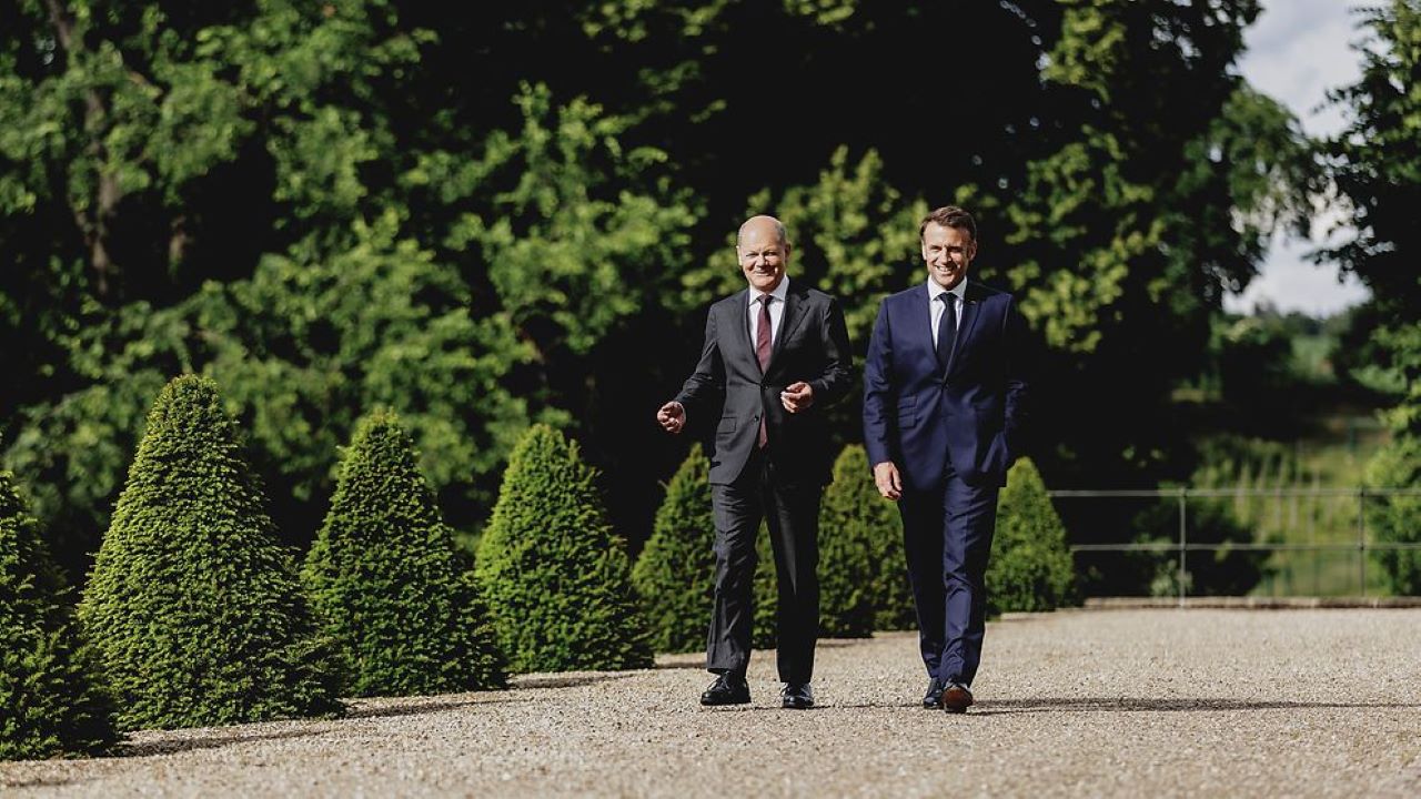 German Chancellor Scholz and French President Macron walking through a park.